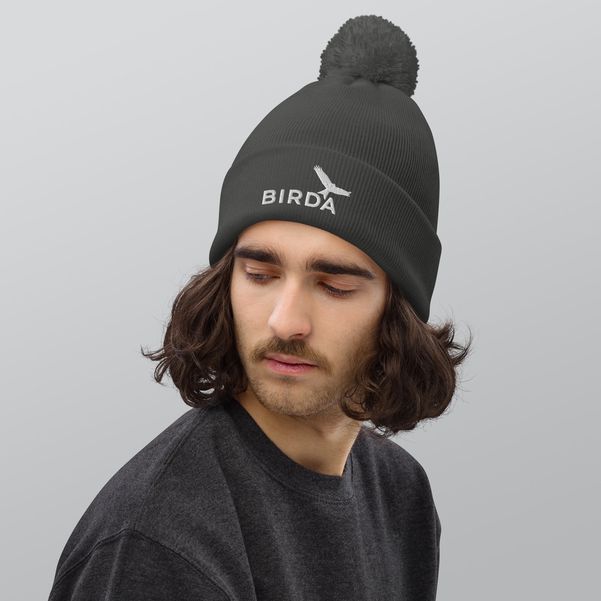 Birda Bird Cuffed Pom-Pom beanie in graphite grey on a man